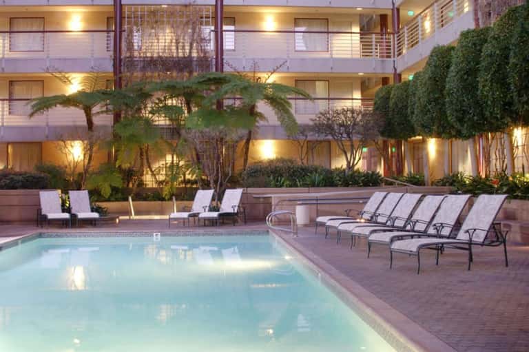 Hotel courtyard pool surrounded by palm trees and lounge chairs with evening lighting
