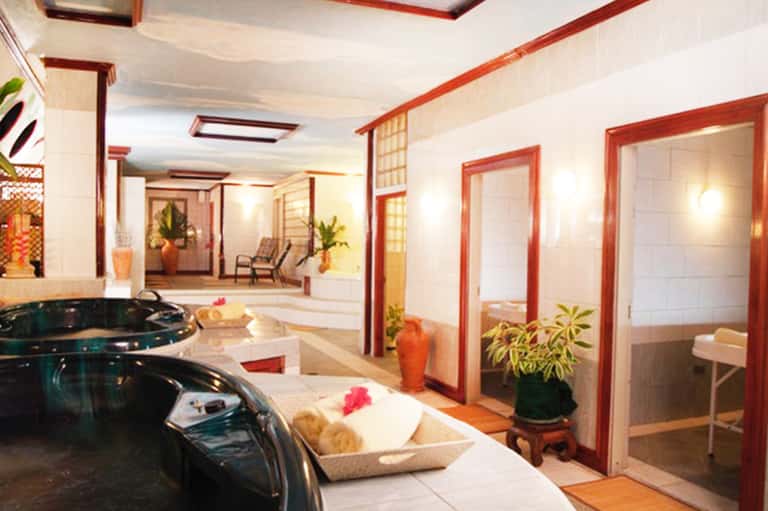 Spa facility with two black soaking tubs, red-framed doors, and white tile flooring