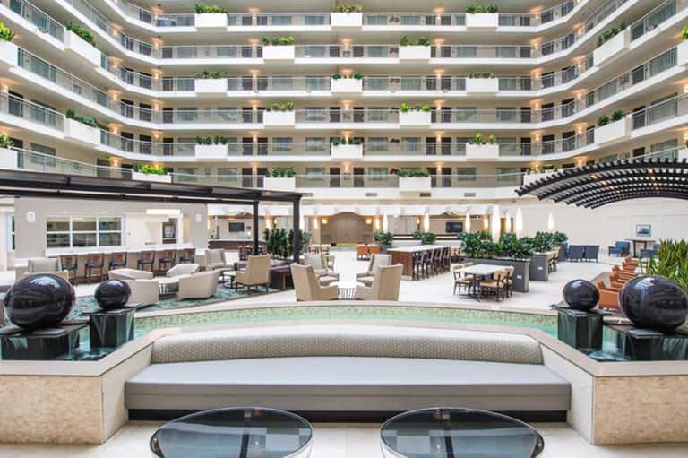 Modern circular hotel atrium lobby with curved balconies, seating areas, and decorative plants