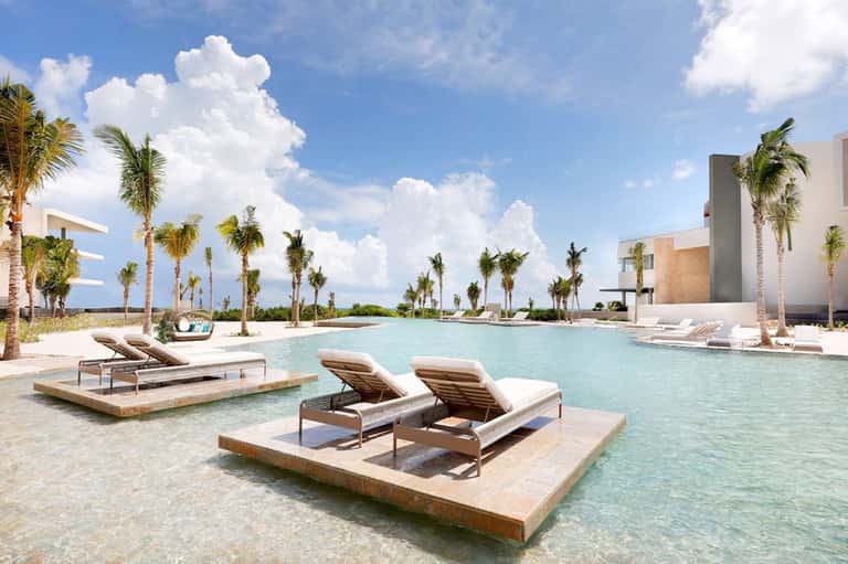 Luxury resort lagoon pool with lounge chairs, palm trees, and modern architecture