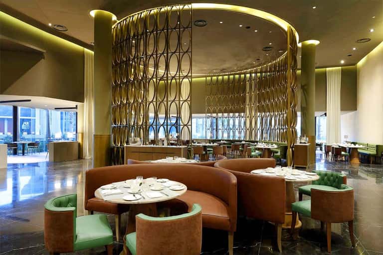 Upscale restaurant with decorative gold geometric dividers, brown leather seating, and ambient lighting