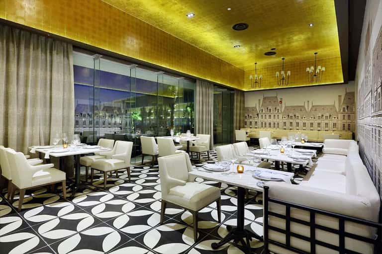 Contemporary restaurant with yellow ceiling, white tables, city views through large windows