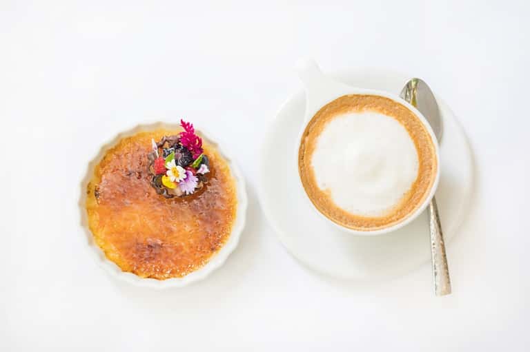 Gourmet dessert plate with brûléed pastry and cappuccino with latte art on white background