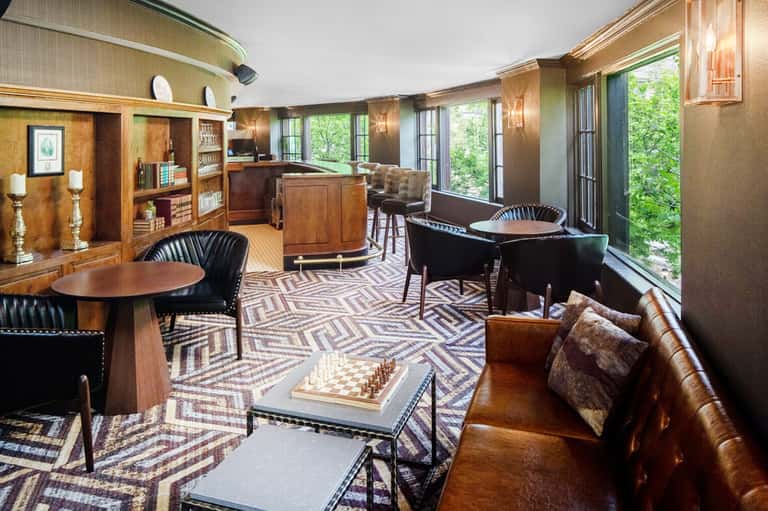 Sophisticated hotel lounge with wood finishes, leather seating, bar, and floor-to-ceiling windows