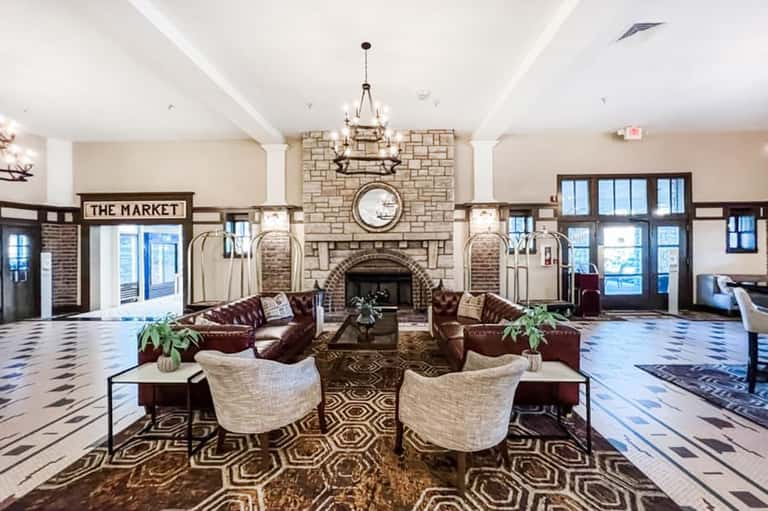 Elegant hotel lobby with fireplace, chandelier, leather seating, and decorative floor