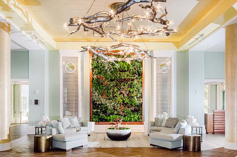Luxury lobby with living wall, branch chandeliers, white seating, and fire feature