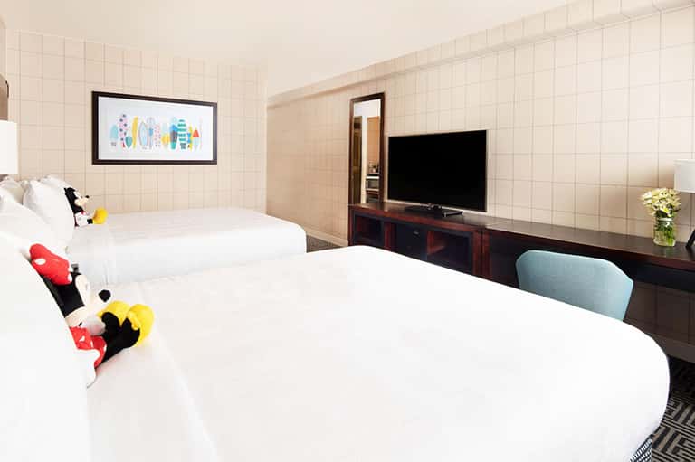 Hotel room with two queen beds, TV, and colorful decorative pillows