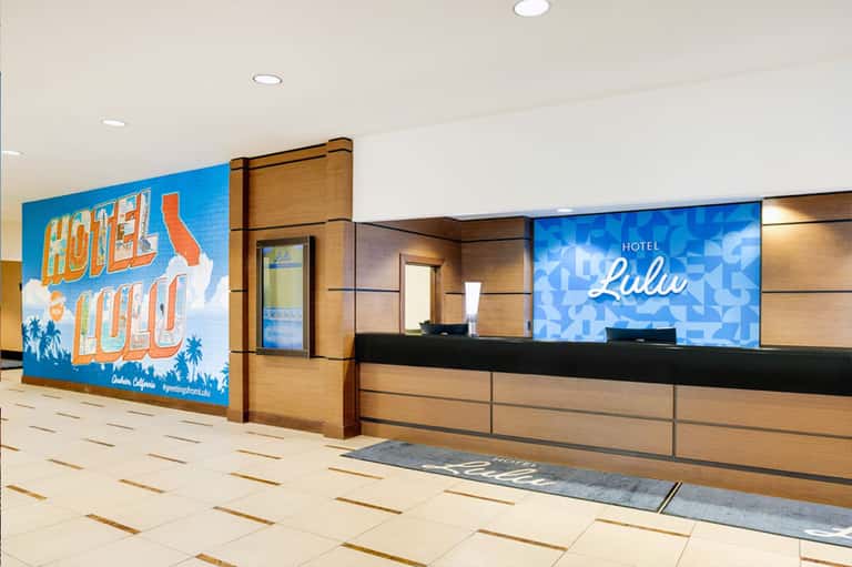 Hotel reception desk with retro sign and blue digital display in modern lobby setting