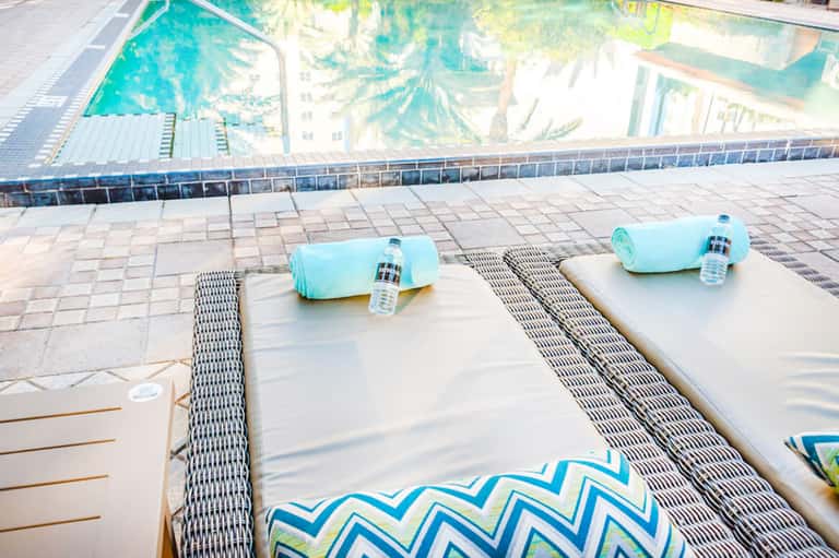 Poolside lounge chairs with towels and water bottles overlooking a resort pool