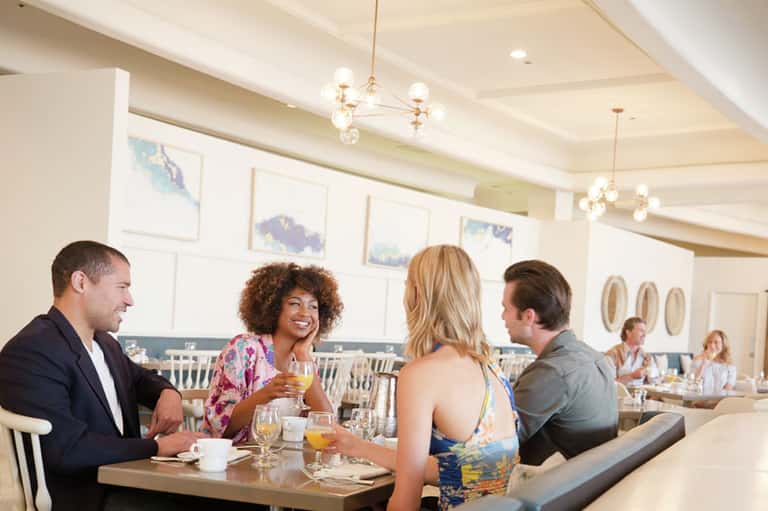 Upscale hotel dining room with guests enjoying breakfast and beverages