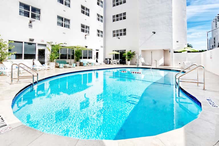 Resort indoor swimming pool surrounded by white walls and large windows in modern facility