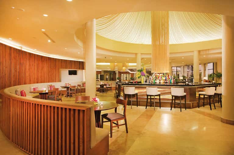 Modern hotel bar and lounge area with warm wood accents, ambient lighting, and comfortable seating