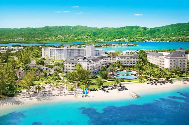 Aerial view of all-inclusive resort nestled between lush mountains and turquoise Caribbean waters