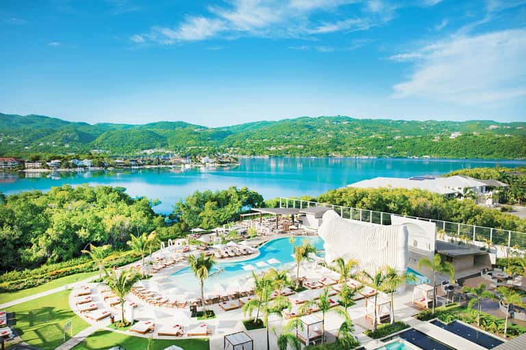 Luxury resort pool overlooking turquoise lake and forested mountains