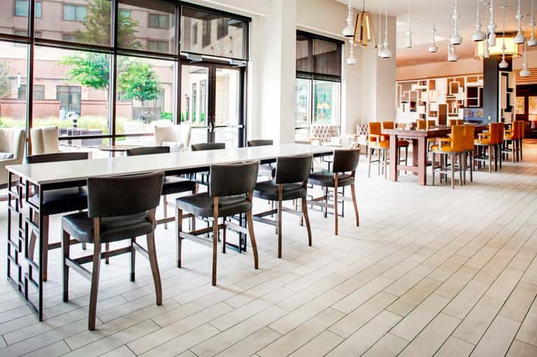 Contemporary hotel dining area with white tables, modern lighting, and floor-to-ceiling windows