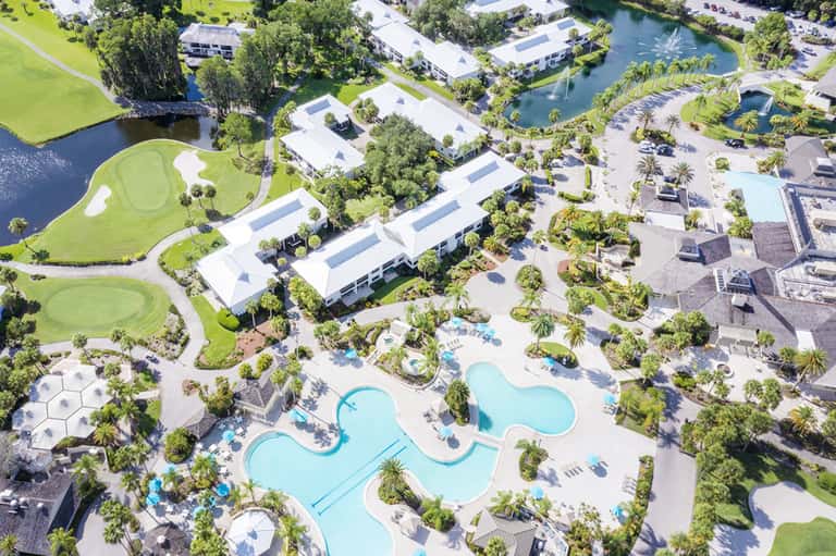 Aerial view of large resort complex with multiple pools, golf course, and lush tropical landscaping
