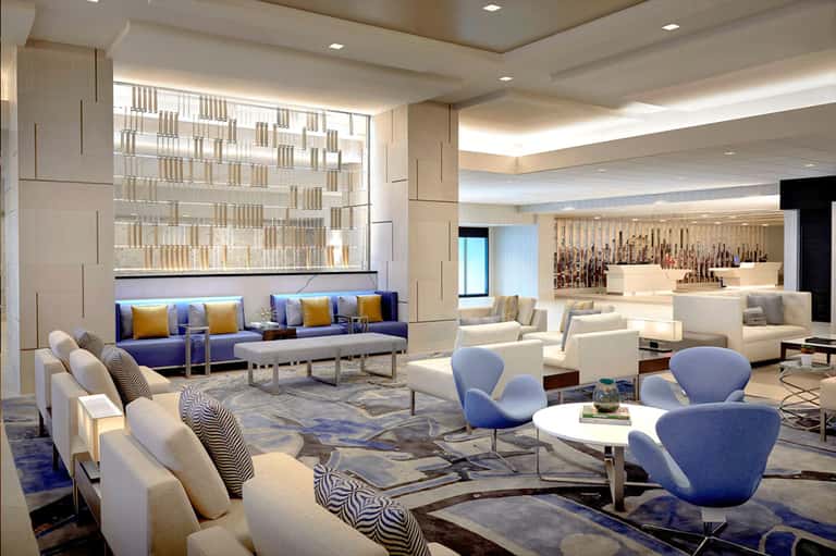 Modern hotel lobby lounge with blue and cream seating, geometric patterns, and wine bar