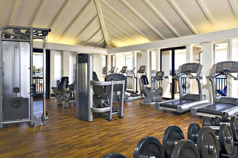 Bright fitness center with exercise equipment, wooden flooring, and large windows overlooking water