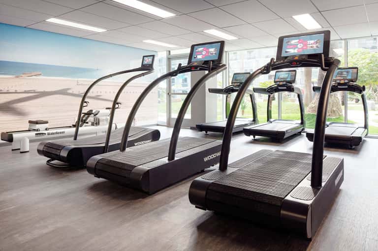 Fitness center with treadmills featuring screens overlooking a beach landscape view