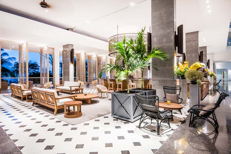 Luxury hotel lobby with modern furnishings, plants, and ocean views