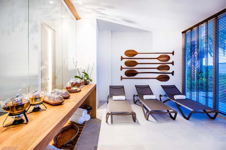 Spa relaxation room with lounge chairs, wooden oar wall art, and ocean view