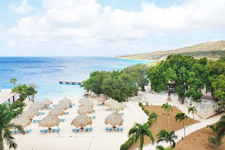 Beachfront resort with thatched umbrellas, white sand, and turquoise water