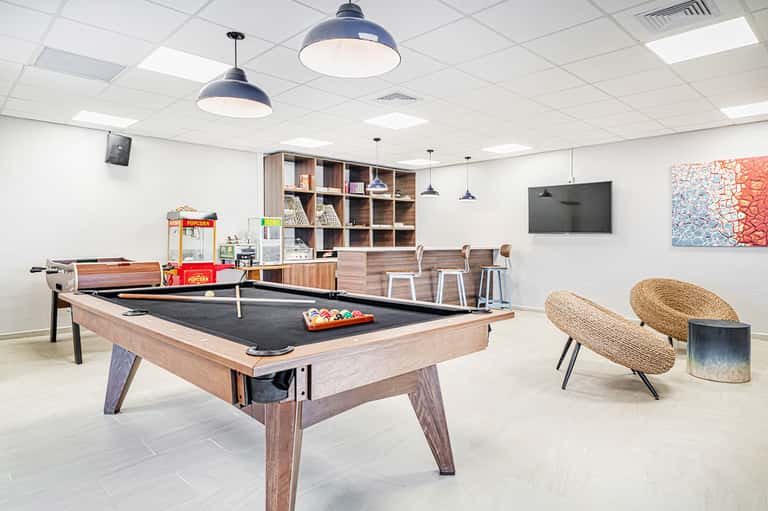 Recreation room with pool table, popcorn machine, shelving, and woven seating chairs