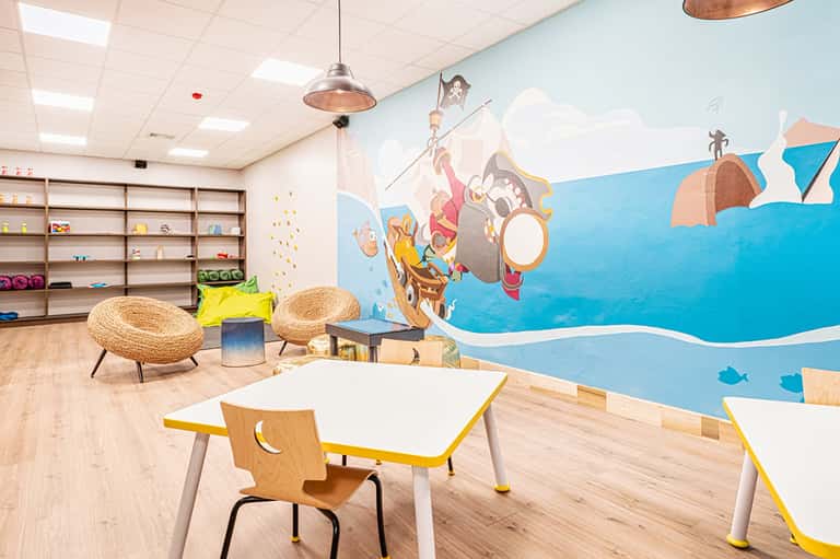 Colorful children's playroom with themed wall mural, wooden furniture, and activity tables