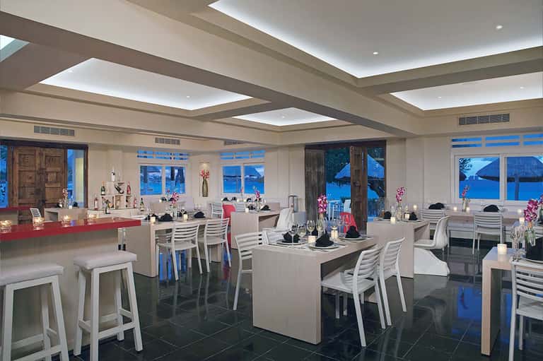 Modern seafront restaurant with floor-to-ceiling windows and ocean view at dusk