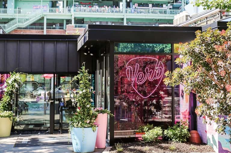 Modern restaurant entrance with neon heart sign and pink and yellow planters