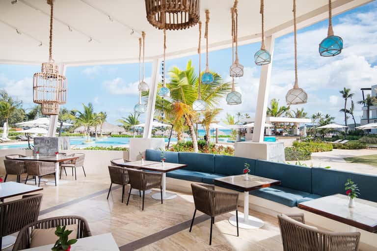 Contemporary lounge area with hanging pendant lights, palm trees, and pool views