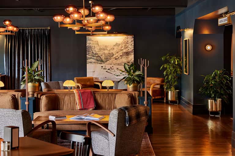 Contemporary hotel lounge with copper pendant lighting, leather seating, and artistic mountain photograph