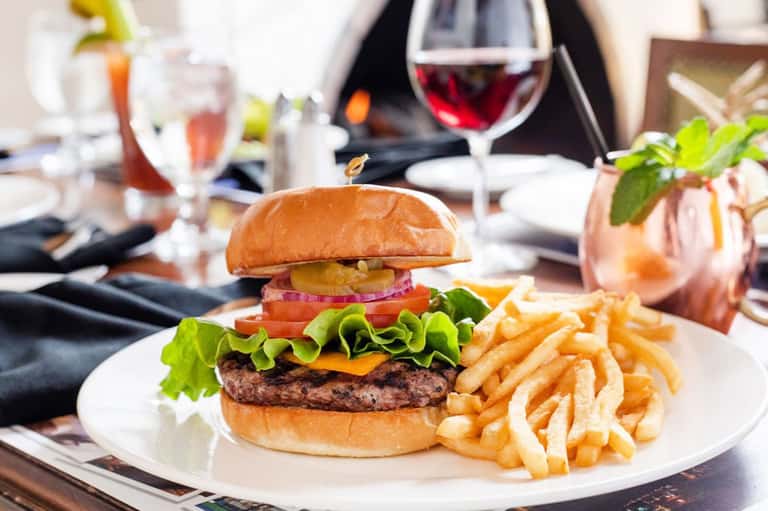 Gourmet burger with fries and cocktails at upscale resort dining table