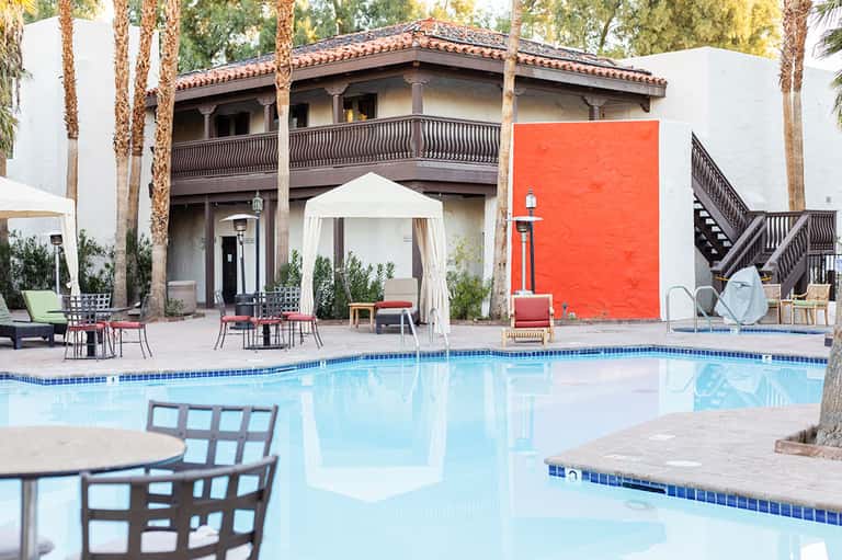 Resort pool with Spanish colonial architecture, palm trees, and lounge seating