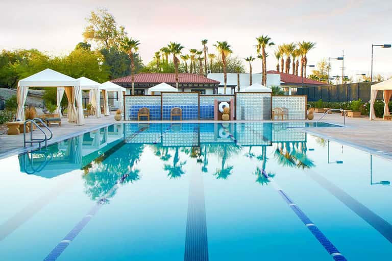 Modern lap pool with lane dividers, white cabanas, and decorative blue tile fence