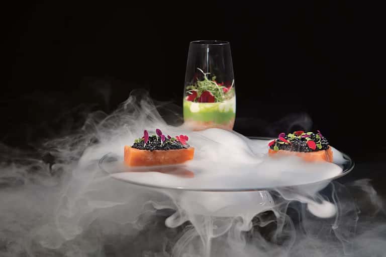 Fine dining plated dishes with microgreens and decorative smoke under glass dome
