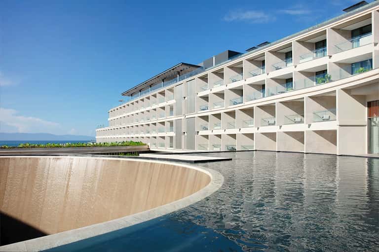 Contemporary white resort building with curved pool and sea view