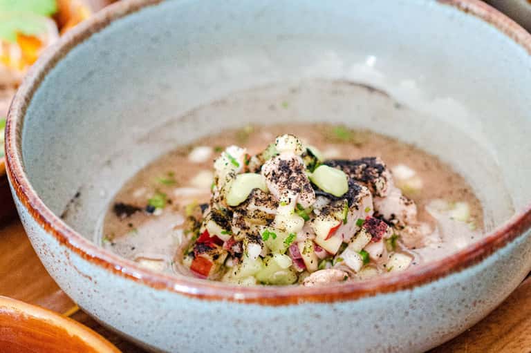 Artfully plated seafood dish in ceramic bowl with garnish and spices