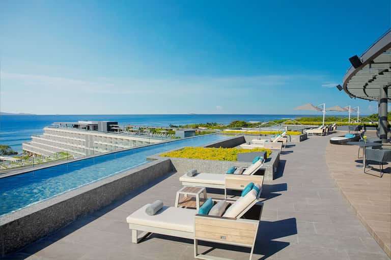 Modern rooftop pool deck with contemporary loungers and coastal landscape view