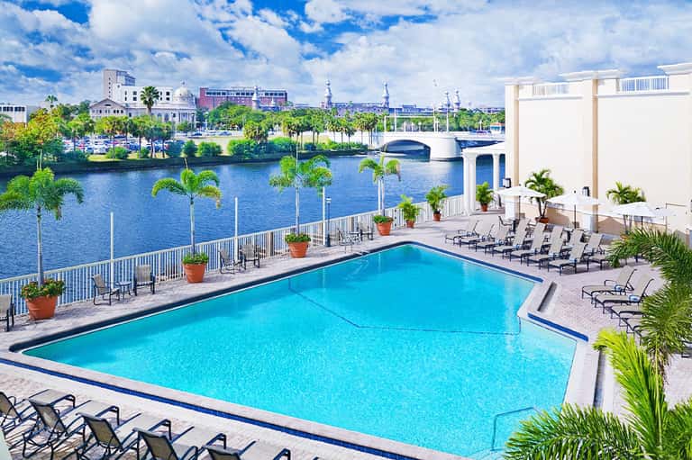 Waterfront hotel pool overlooking river, palm trees, historic downtown buildings and bridge