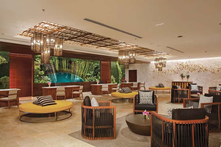 Contemporary lounge with tropical wall mural, colorful round tables, and artistic lighting