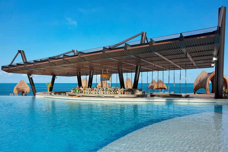 Luxury resort pool bar with geometric structure overlooking turquoise ocean