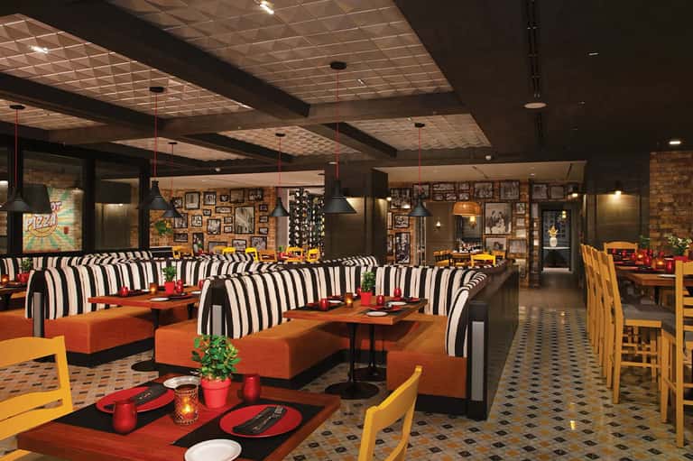 Vibrant restaurant interior with striped seating, orange accents, and photo-covered walls