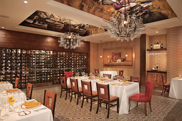 Fine dining wine cellar room with crystal chandeliers and white tablecloth tables