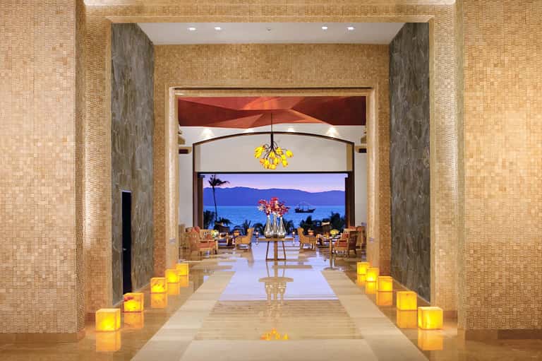 Elegant spa entrance with candlelit pathway, ocean view, and contemporary interior design