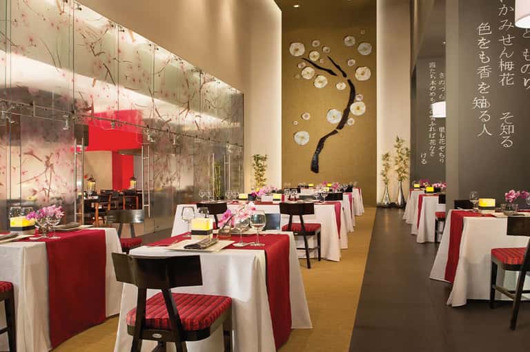 Modern dining room with red and white accents, artistic wall installations, and contemporary table settings