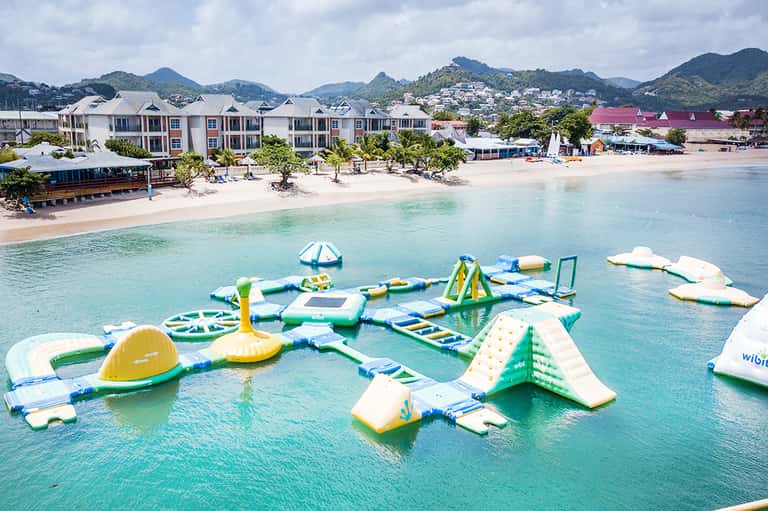 Inflatable water park with various floating obstacles and slides in turquoise shallow water