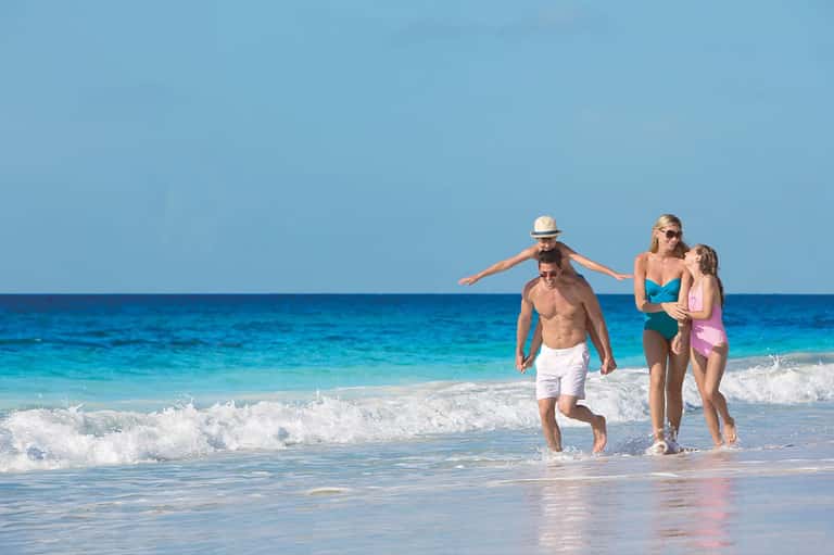 Family running into ocean waves on a sunny beach day