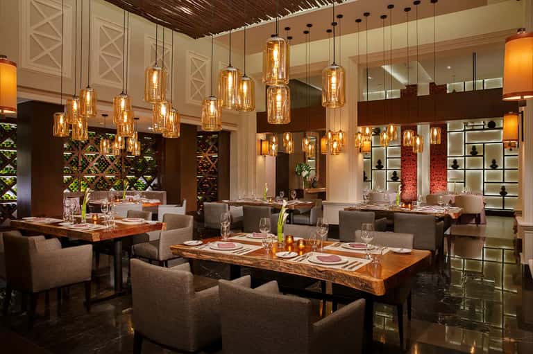 Upscale restaurant dining room with amber pendant lights and wooden tables