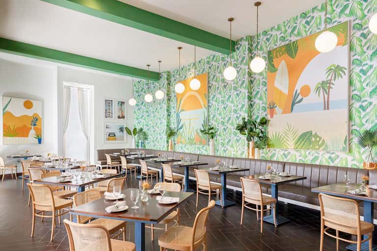 Modern restaurant interior with tropical wallpaper and green beam ceiling